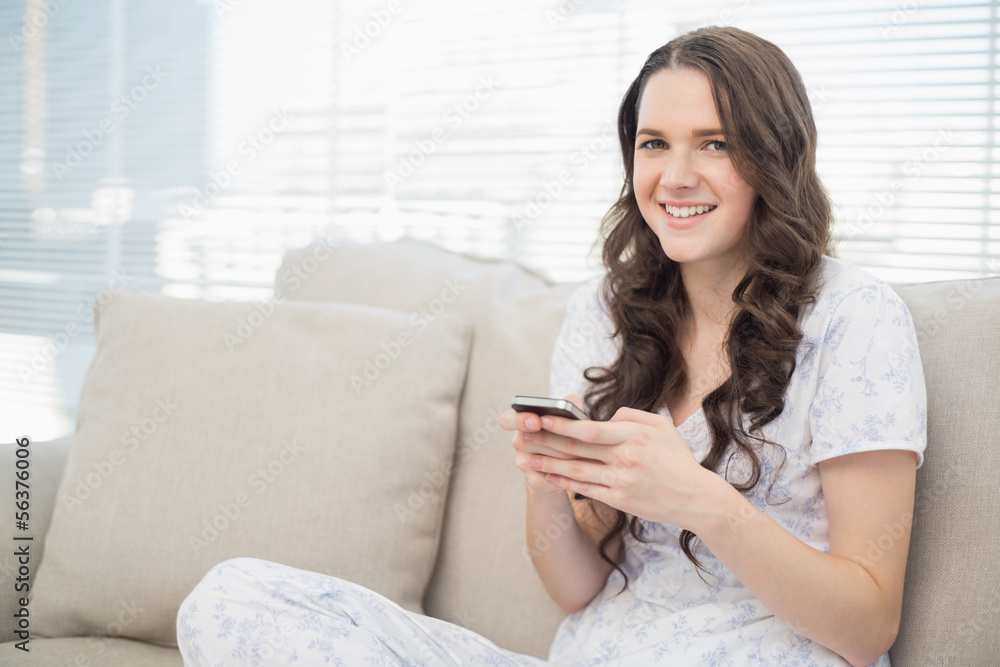 Smiling pretty woman in pyjamas sending a text Smiling pretty woman in pyjamas sending a text