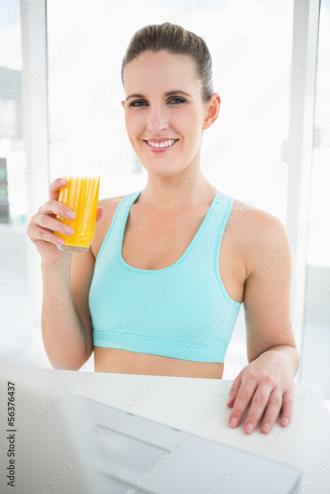 Happy woman in sportswear holding orange juice