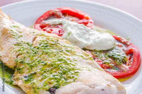 Filetto di merluzzo con pesto e contorno di caprese photo