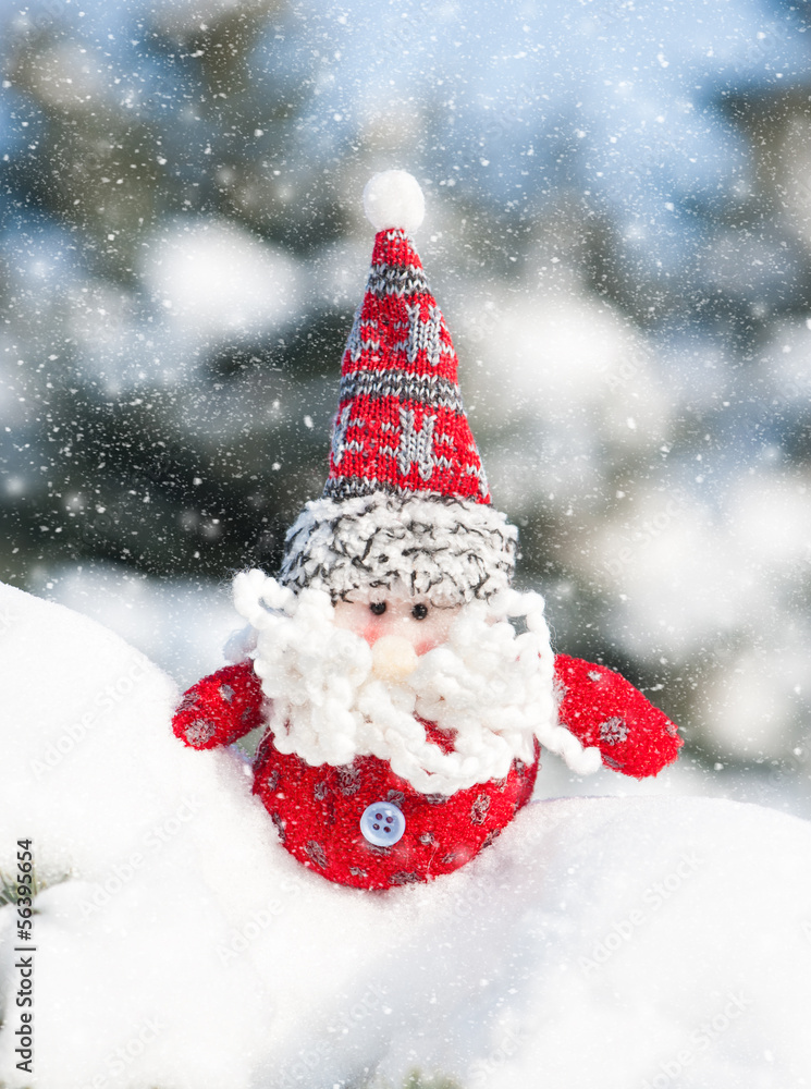 santa toy in snowdrift with snowfall