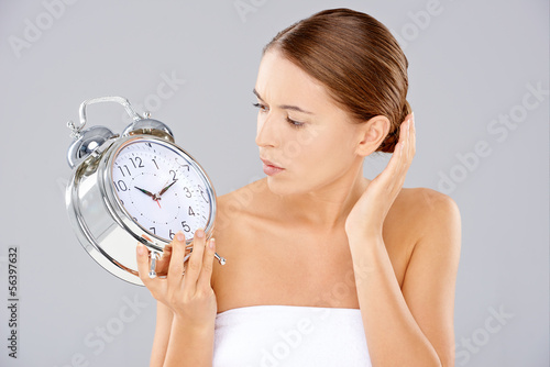 Woman looking at an alarm clock in consternation