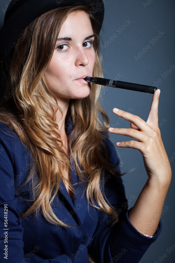 Obraz premium Elegant woman holding and smoking e cigarette