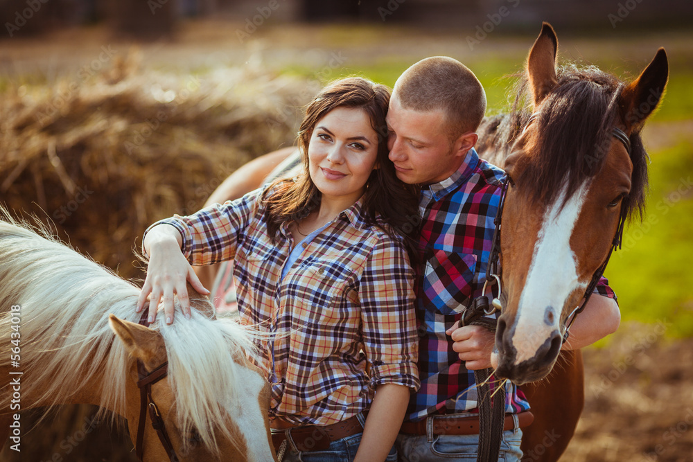 couple standing on farm with horses - obrazy, fototapety, plakaty 