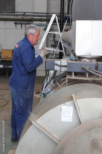 An engineer painting a large industrial steam boiler