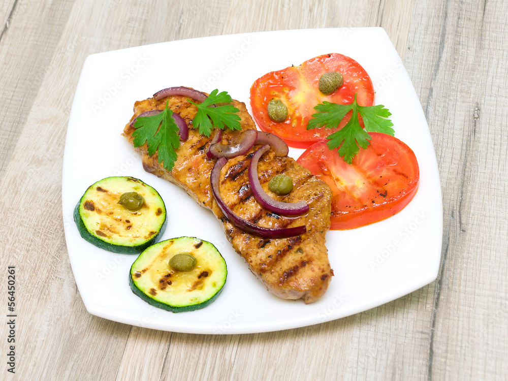 piece of roasted meat with vegetables on a white plate piece of roasted meat with vegetables on a white plate