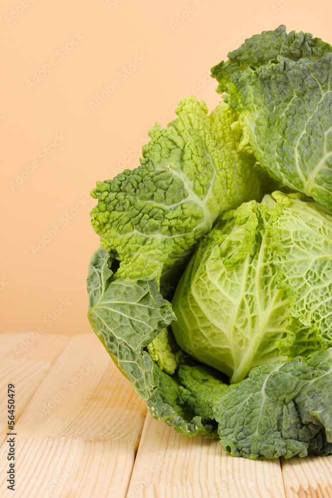 Fresh savoy cabbage on wooden table on beige background Fresh savoy cabbage on wooden table on beige background