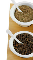 Crédence de cuisine Épices Aromatic allspice berries and cumin seeds in white bowls with spoons on wooden board, culinary spices for cooking  © Africa Studio
