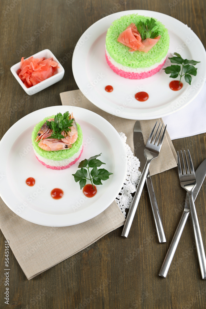 Colored rice on plates on napkins on wooden table Colored rice on plates on napkins on wooden table