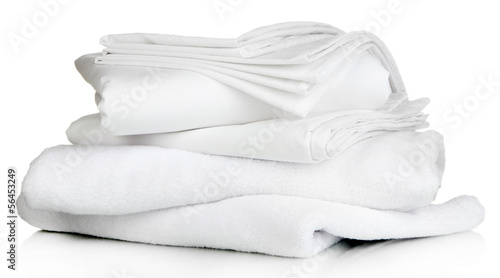 Stack of clean bedding sheets and towels isolated on white