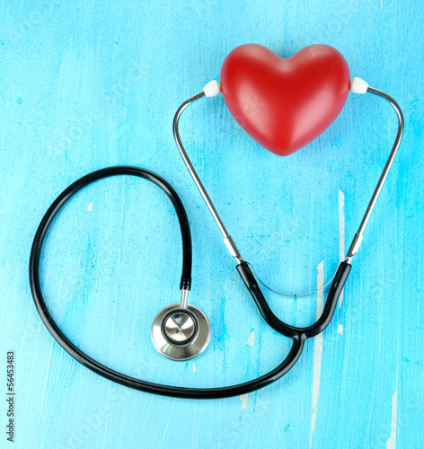 Stethoscope and heart on wooden table close-up