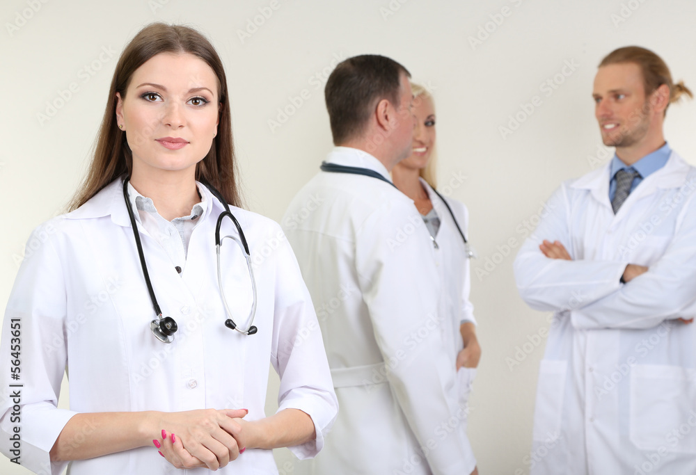 Doctor standing in front of coworkers on grey background Doctor standing in front of coworkers on grey background