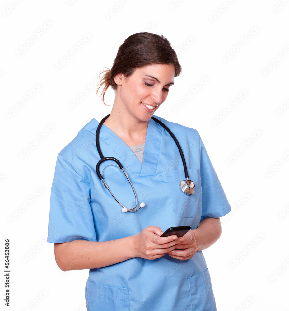 Charming nurse smiling while sending a text Charming nurse smiling while sending a text