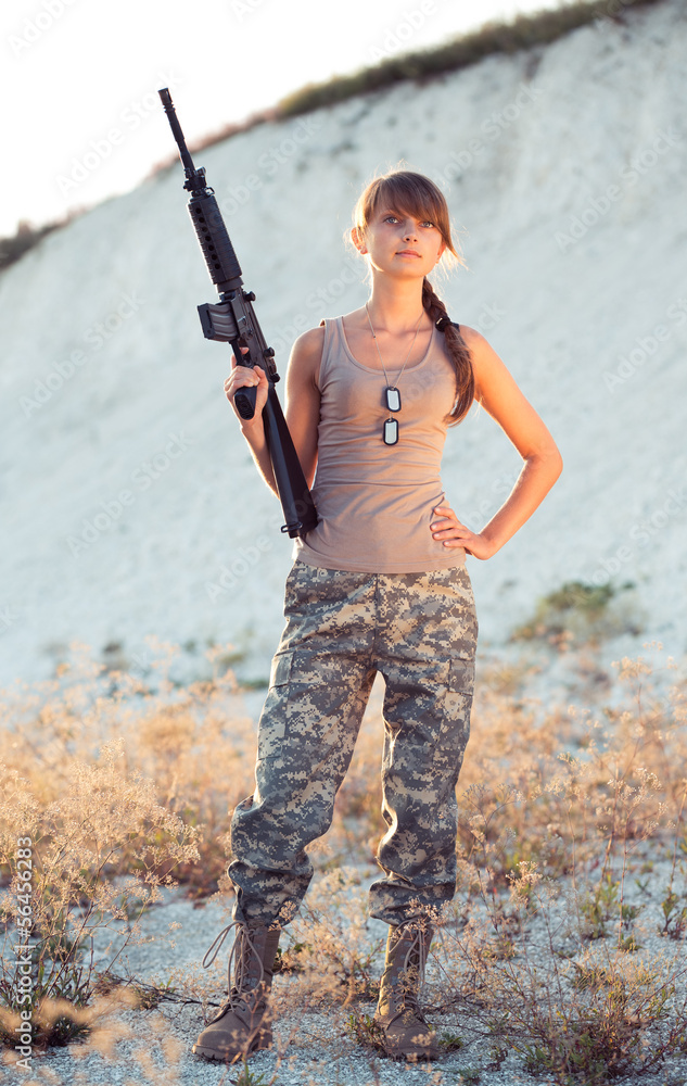 Female soldier dressed in a camouflage with a gun in the locatio Female soldier dressed in a camouflage with a gun in the locatio
