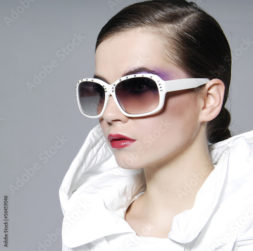 Portrait of fashion model in sunglasses posing on gray