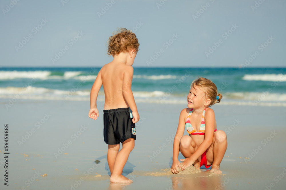 two happy kids playing at the beach in the day time two happy kids playing at the beach in the day time