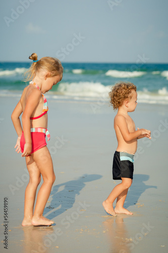 two happy kids playing at the beach in the day time
