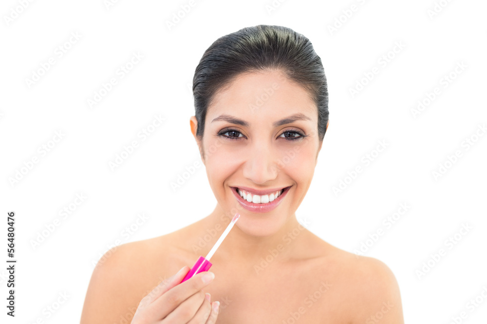 Brunette applying lip gloss and smiling at camera Brunette applying lip gloss and smiling at camera
