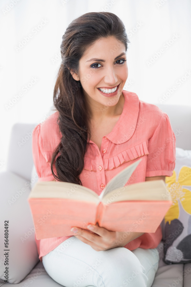 Pretty brunette sitting on her sofa reading a book Pretty brunette sitting on her sofa reading a book
