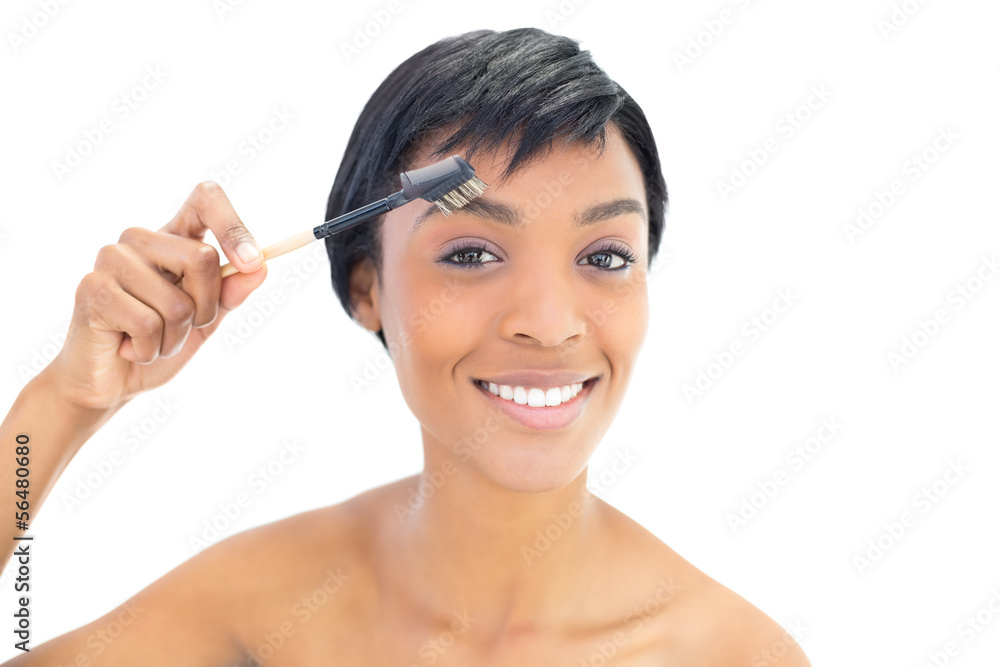 Happy black haired woman brushing her eyebrows Happy black haired woman brushing her eyebrows