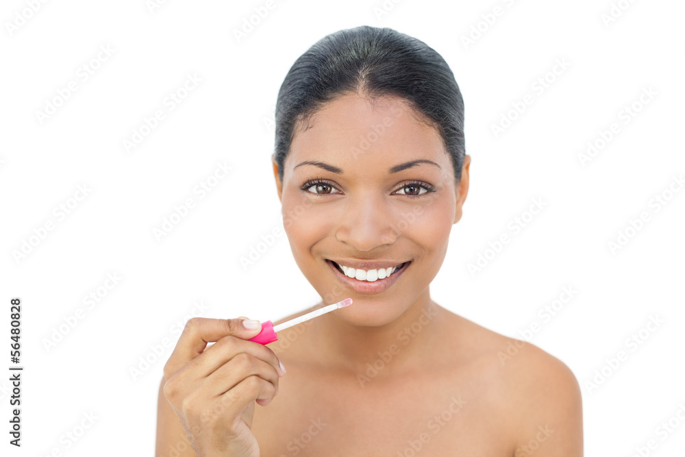 Smiling black haired model applying lip gloss Smiling black haired model applying lip gloss