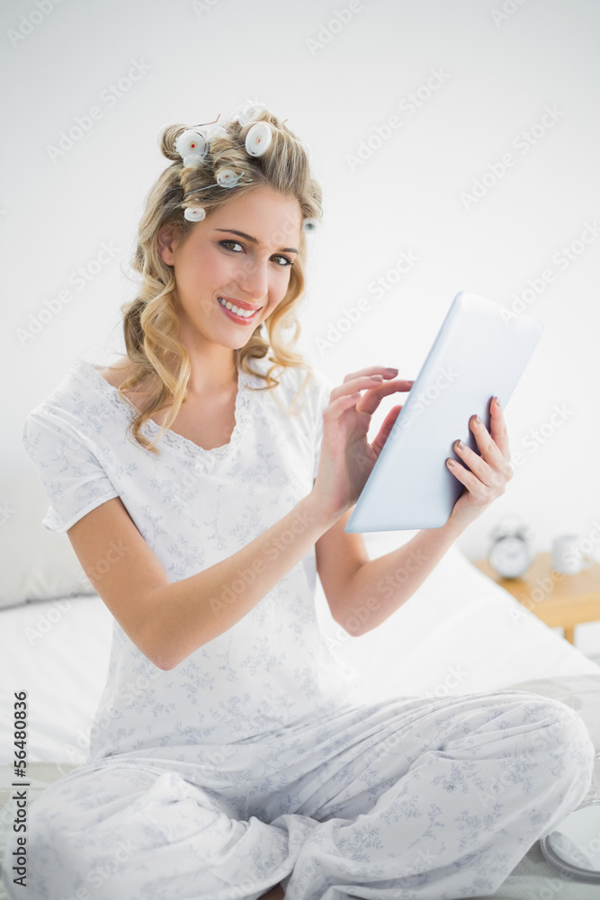 Happy cute blonde wearing hair curlers using tablet Happy cute blonde wearing hair curlers using tablet