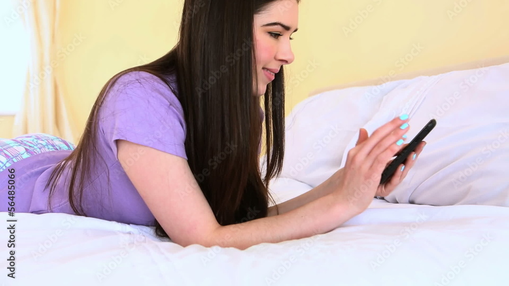 Woman text messaging on bed Woman text messaging on bed