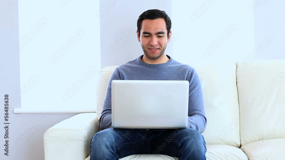 Man using a laptop on the couch Man using a laptop on the couch