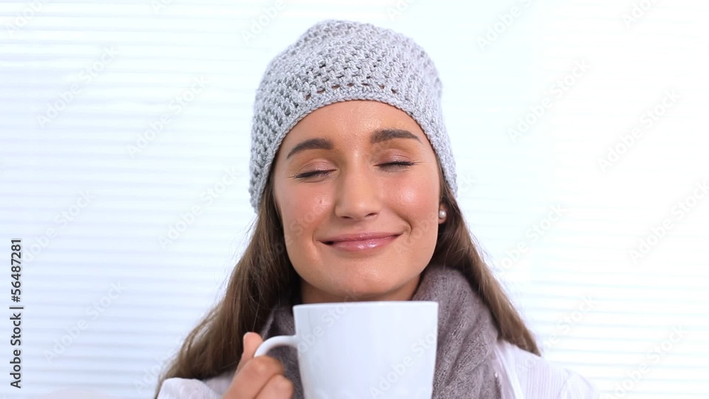 Young woman with hat and scarf smelling her cup Young woman with hat and scarf smelling her cup