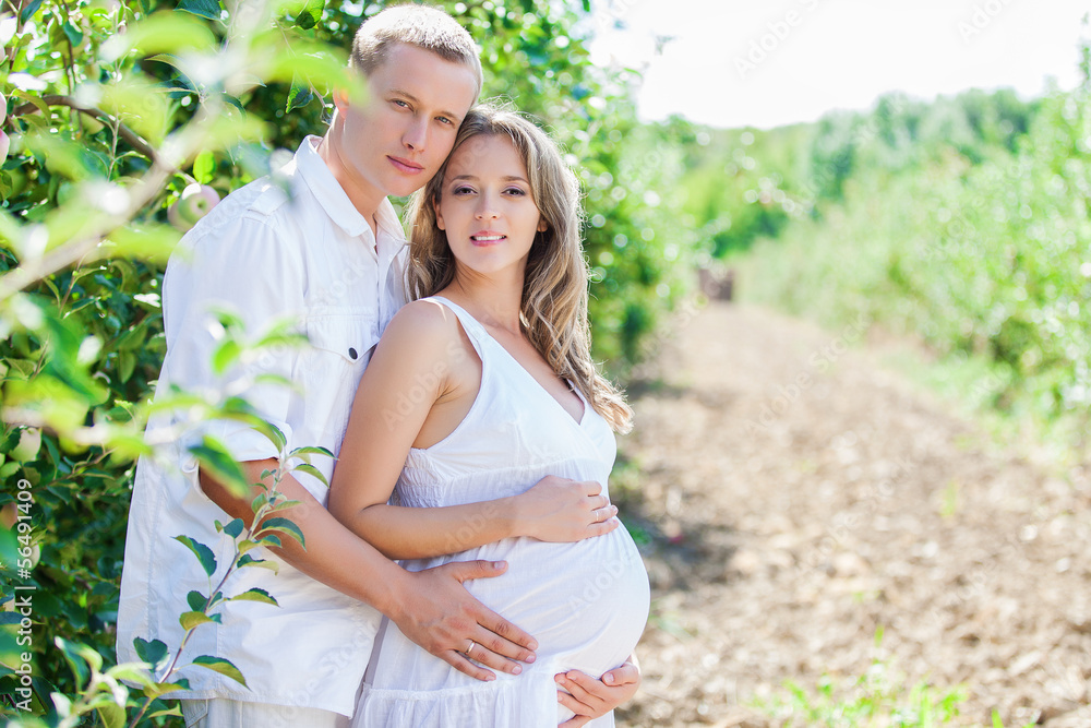 Obraz premium Family, husband and pregnant wife posing in green garden
