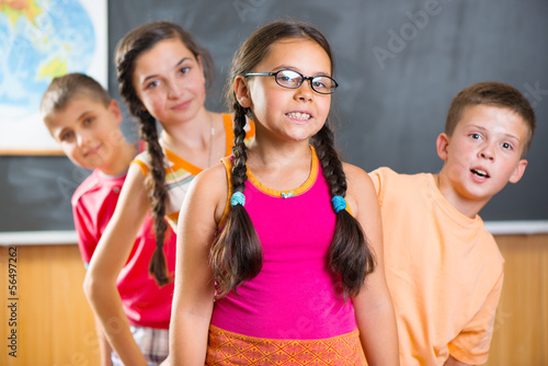 Four schoolchildren standing in classroom against blackboard