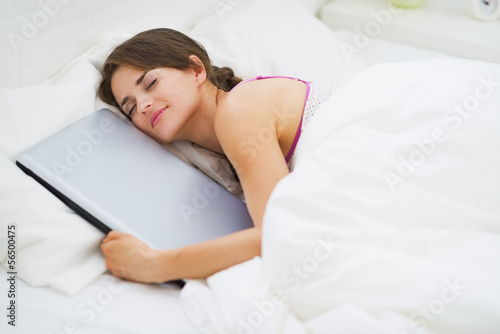 Fotografia Young woman hugging laptop while sleeping