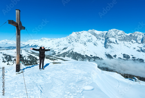 Tourist near the cross on winter mountain top