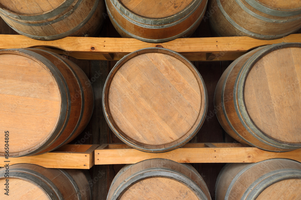 Horizontal wooden wine barrels in cellar shelf.