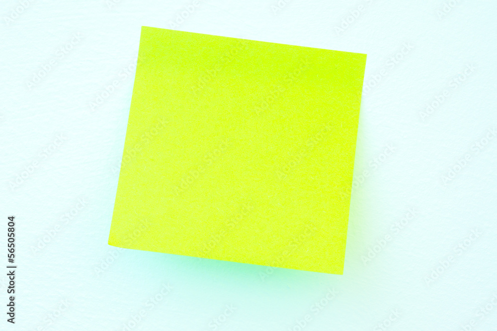 A blank sticky note with a notebook on the wall A blank sticky note with a notebook on the wall