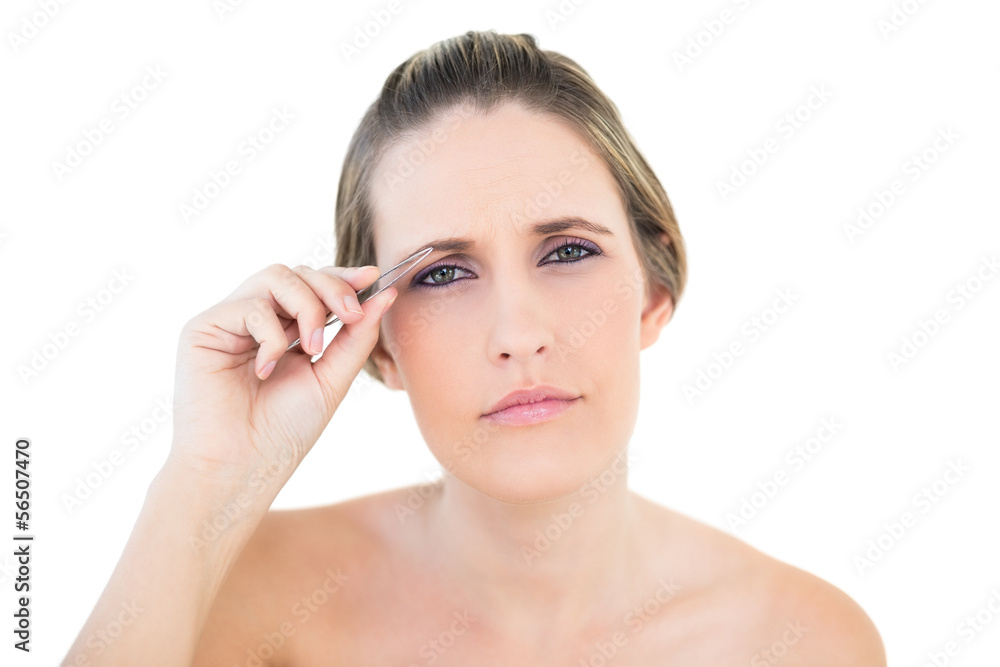Unsmiling woman using tweezers looking at camera