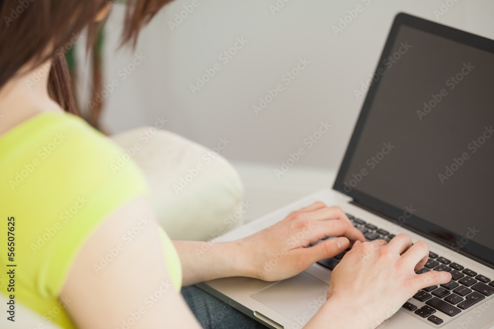 Girl typing on laptop sitting on a sofa Girl typing on laptop sitting on a sofa