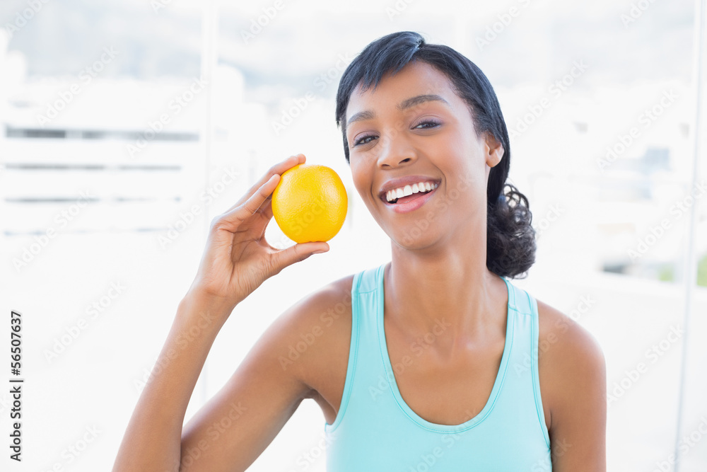 Delighted black haired woman holding an orange Delighted black haired woman holding an orange