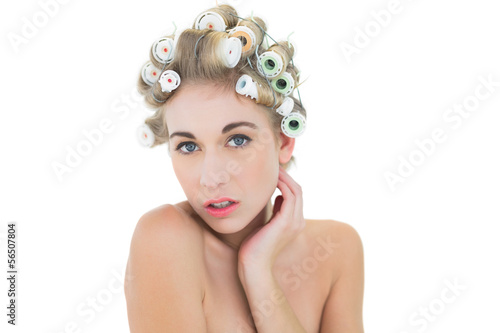 Pensive blonde model in hair curlers looking at camera