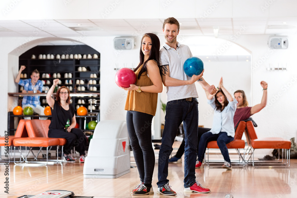 Fototapeta premium Young Man And Woman With Bowling Balls in Club