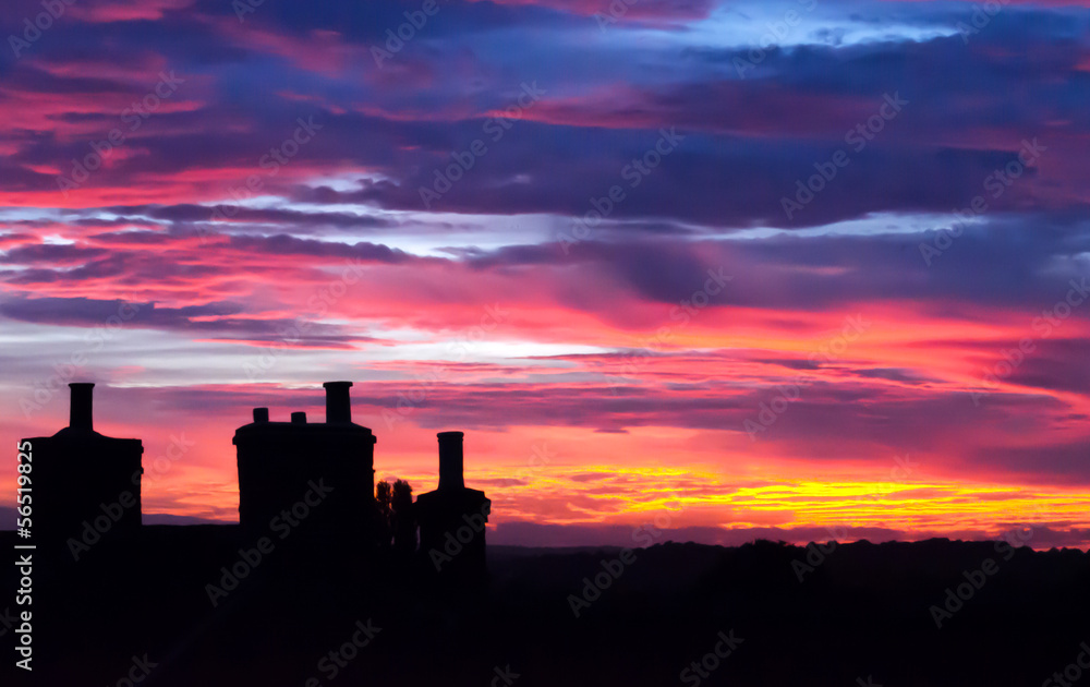 Beautiful sunset with house chimneys silouette