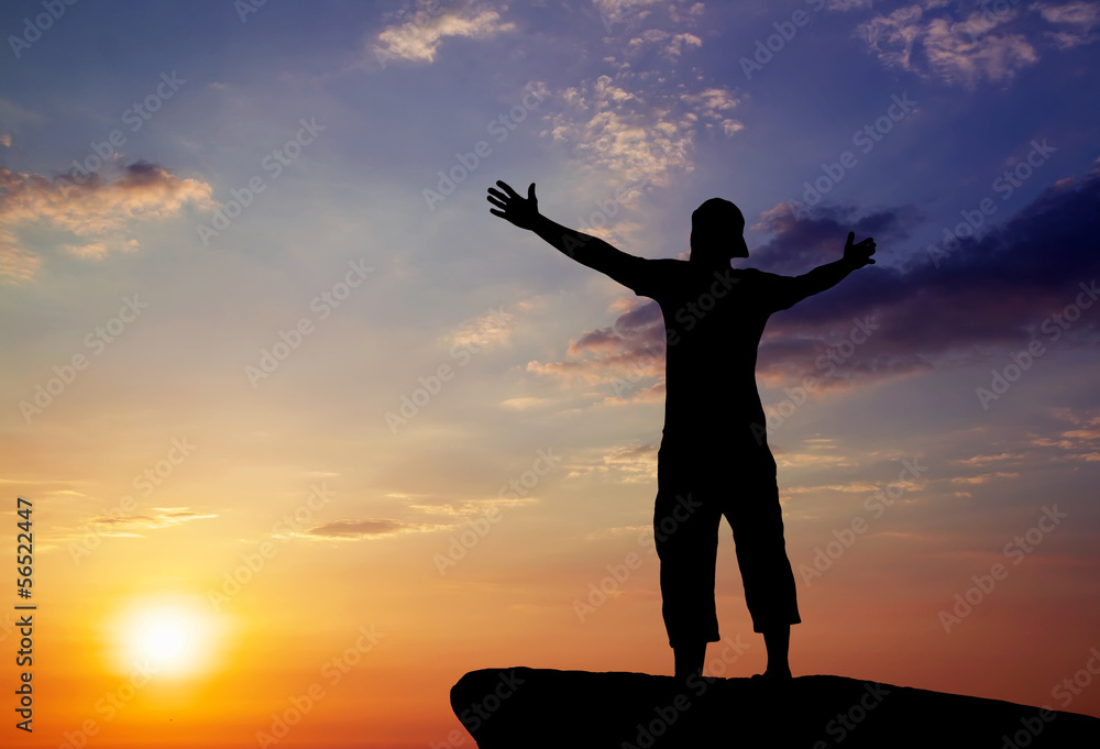Fototapeta premium Silhouette of a man on a mountain top at sunset