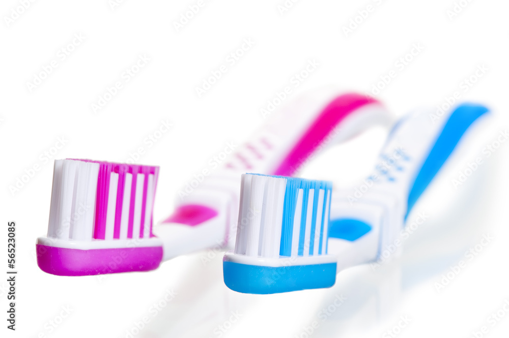 blue and pink toothbrushes lying on a white background blue and pink toothbrushes lying on a white background