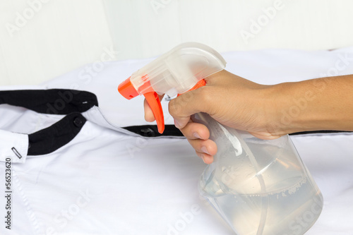 Spraying a shirt with laundry detergent in spray bottle.