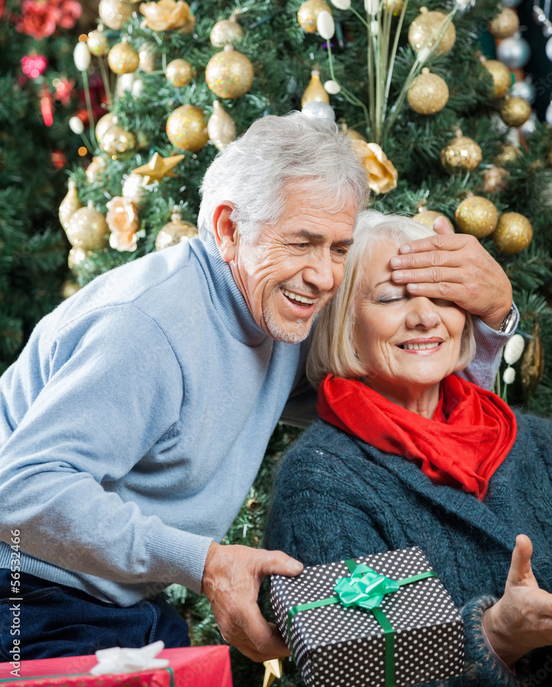Man Surprising Woman With Christmas Gifts In Store Man Surprising Woman With Christmas Gifts In Store