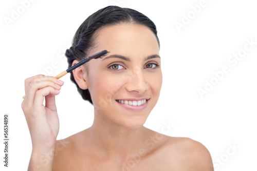 Smiling young brunette using eyebrow brush