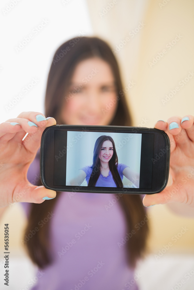 Happy girl taking a photo of herself with her mobile phone