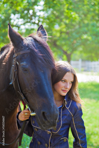 Young girl walking with a horse in the garden. © lenkusa