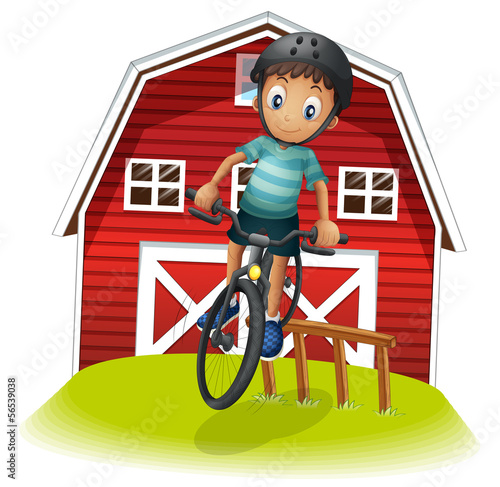 A boy playing with his bike in front of the barnhouse