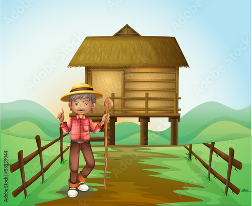 An old man with a cane standing in front of the nipa hut