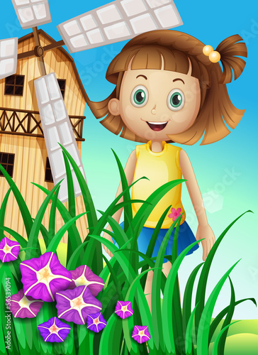 A girl watching the flowers in the garden near the windmill